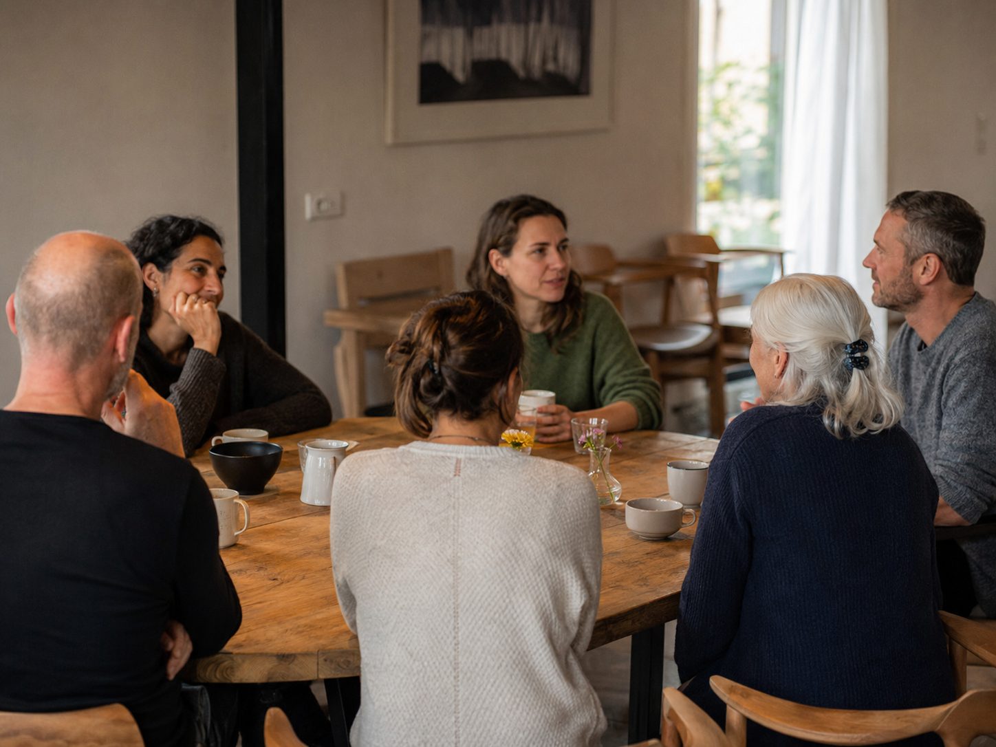 Conversation in a small group around a wooden table in the retreat house